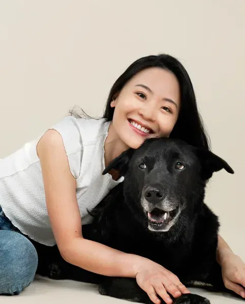 A team member smiling beside her calm black dog