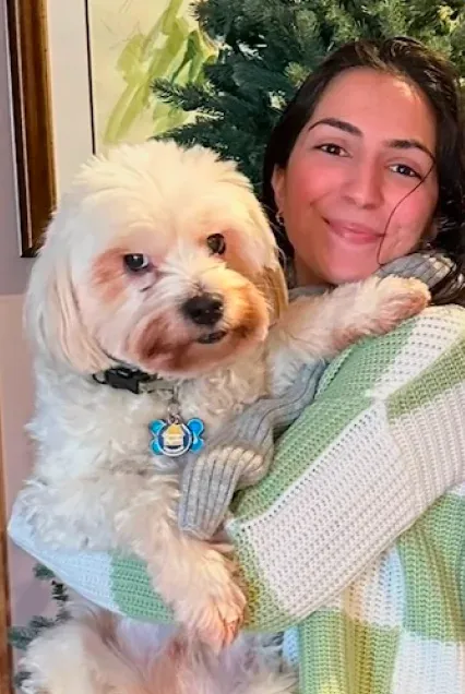 A team member cuddling her fluffy white dog by the tree